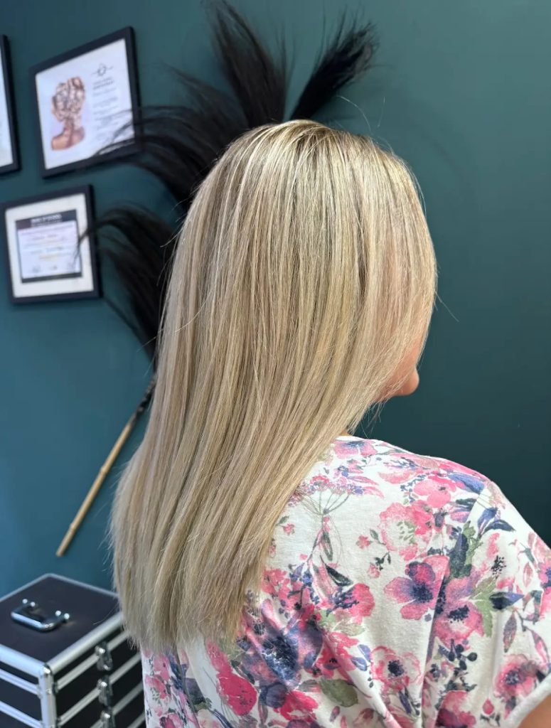 Kundin mit blondem, glatten Haar – Rückansicht nach dem Styling